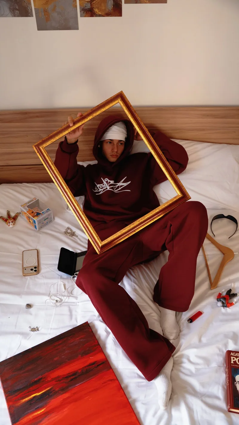 Lookbook Leave: coordinato bordeaux sul letto con cornice dorata.